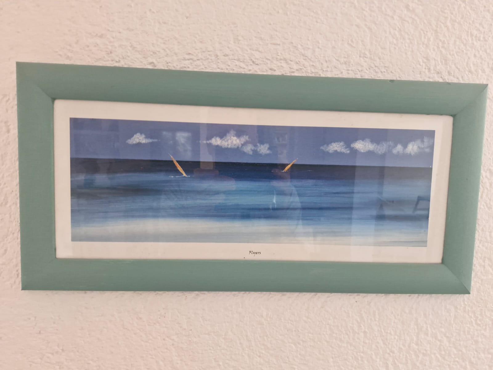 Framed seaside painting on wall